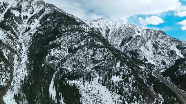 Frisco Gulch steep mountain slopes with snow patches and dense forest below, aerial drone overview