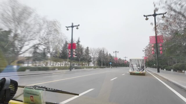 shot from a vehicle's perspective traveling down a wide city road in China on an overcast day