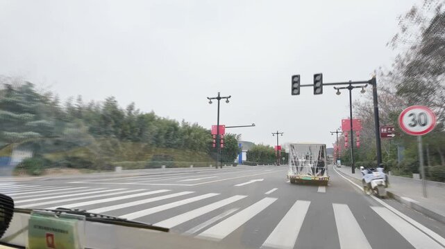 shot from a vehicle's perspective traveling down a wide city road in China on an overcast day