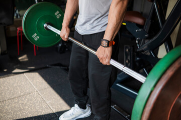 Fototapeta premium Close-up of an anonymous athlete performing a deadlift with a double overhand grip to build strength and improve lifting form