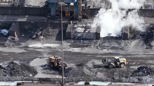 Bulldozers moving coal piles in steel mill yard