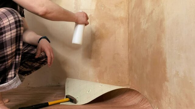 Hand spraying anti mold solution on wall indoors, home repair process, cleaning and renovation concept.