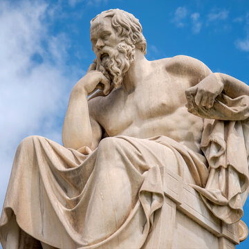 Seated Socrates statue in a thoughtful pose against a vivid blue sky, symbolizing philosophy, reflection, and classical Greek heritage.