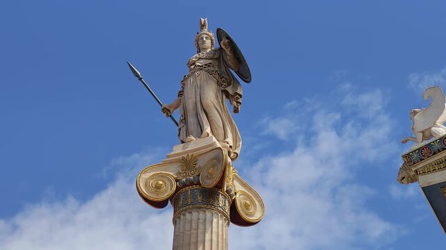 Vew of the bronze-detailed Athena statue and the Sphinx on the Academy of Athens pediment. A stunning display of neoclassical sculpture against the blue sky.