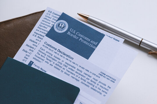 High angle view of U.S. Customs Declaration Form 6059B with passport and silver pen on a desk