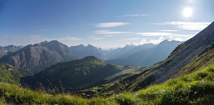 Alpine mountain layers in misty blue light at sunset, scenic valley vista from Lechquellengebirge towards Inntal, Vorarlberg, Austria