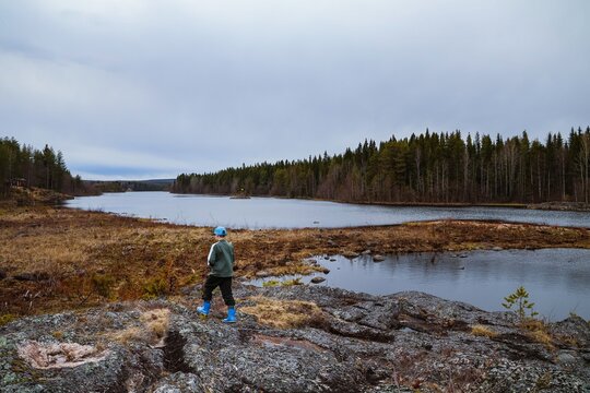Child walking on rocky lakeshore in Finnish wilderness exploring nature