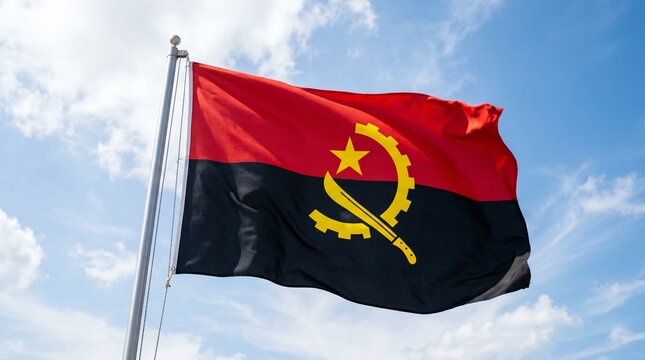 The Angolan flag waves beneath a bright blue sky, symbolizing strength, independence, and unity through its red, black, and yellow emblem of revolution and progress.