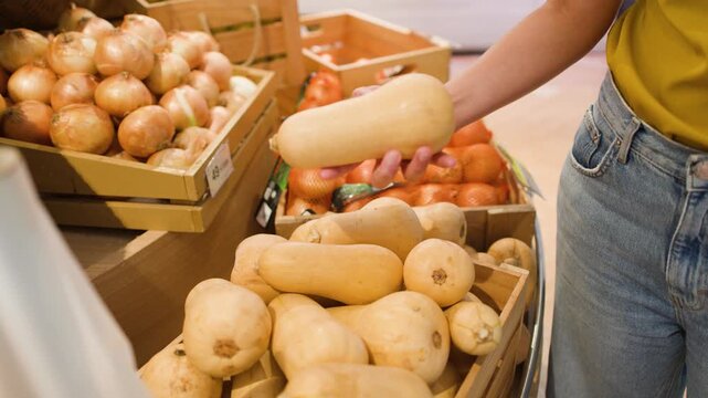 Customer Inspecting Fresh Butternut Squash in a Grocery Store Produce Section
