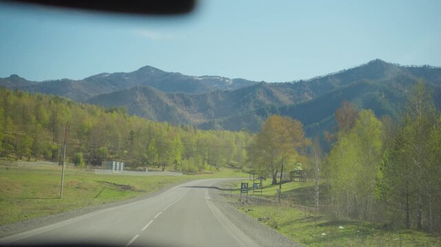 Traveling Along Open Roads With Mountain Views. Driving On Clear Highway Past Mountains And Lush Fields. Cruising Along Vast Highway With Mountain Silhouettes Under Bright Blue Sky