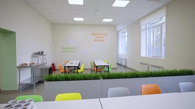 Spacious school canteen features tidy tables colorful chairs near decorative walls. Atmosphere becomes bright clean and welcoming