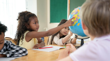 School children exploring a globe together during a geography lesson © Wosunan