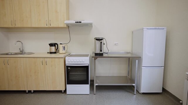 Functional kitchen corner features stove sink and storage cabinets. Minimalistic space equipped for simple cooking during class time