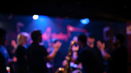 Naklejka premium Energetic crowd enjoying live music performance in a dark club setting