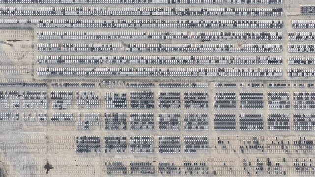 Vertical aerial view of organized automobile storage yard beside green port road