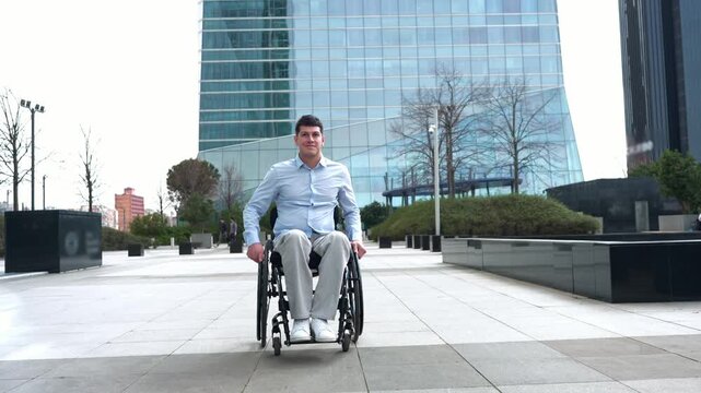 Determined disabled young businessman moving in a wheelchair in a modern business district. Man with a disability overcoming challenges