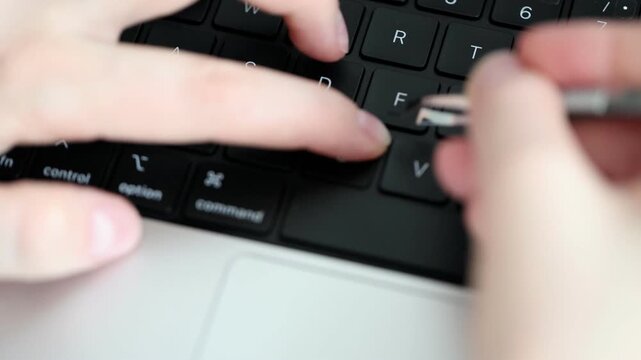 Hands applying letter stickers with tweezers on an English keyboard, adding Cyrillic alphabet characters for multilingual typing