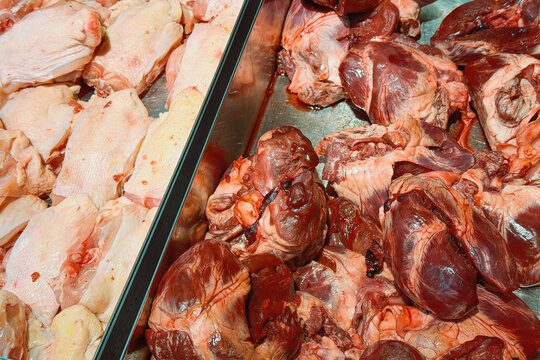 Fresh uncooked poultry cuts and animal organ meat displayed for sale