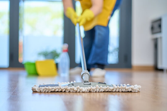 Housekeeping, cleaning and woman maid with a mop cleans the living room floor at a office or workplace. Housemaid and cleaner and housewife washes the ground for bacteria, dust or dirt in her home.