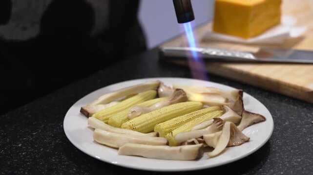 Flambeing Bamboo Shoots and Mushrooms with Kitchen Torch on White Plate Japanese Cooking