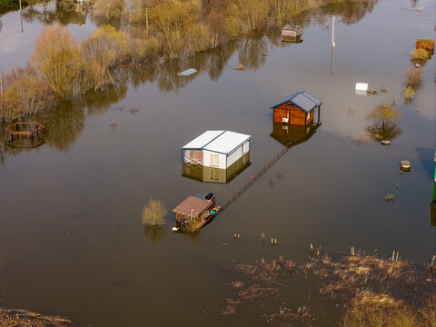 Aerial view of small houses and cabins surrounded by floodwaters and bare trees in Kedainiai, Kaunas County, Lithuania.