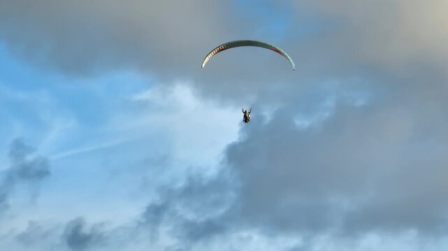 Person parasailing high above the Nusa Dua coast over the Indian Ocean, enjoying incredible aerial views and feeling freedom during adventure sports activity in Bali, Indonesia