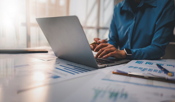 Confident business man point to graphs and charts to analyze market data, balance sheet, account, net profit to plan new sales strategies to increase production capacity.
