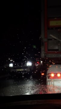 Driving behind cars at night in the rain through a wet windshield