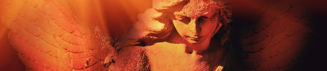 Naklejka premium Dramatic angel statue illuminated by fiery orange light with copy space