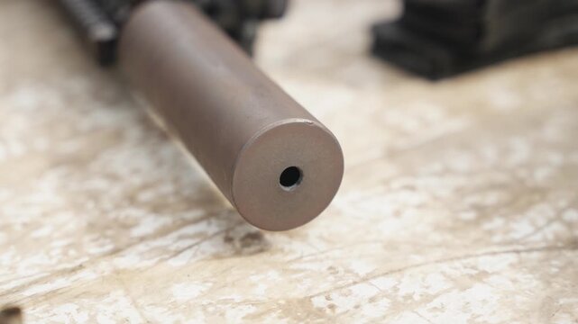 Close up of firearm suppressor attachment showing cylindrical design and metal surface detail