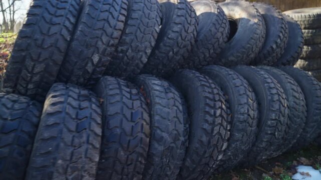 Stack of used truck tires piled outdoors showing rubber texture and industrial recycling scene