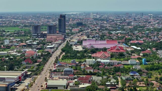 Drone footage capturing a closer perspective of Latsavong Tower, the tallest building in Laos, with a partial view of the National Convention Center Laos nearby. Showcasing modern architecture, govern