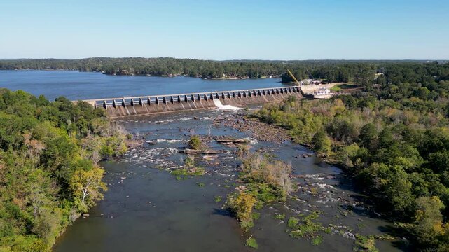 Oliver Dam on Chattahoochee River with spillway releasing water into rocky downstream channel and Lake Oliver reservoir above hydroelectric facility operated by Georgia Power anticlockwise orbit