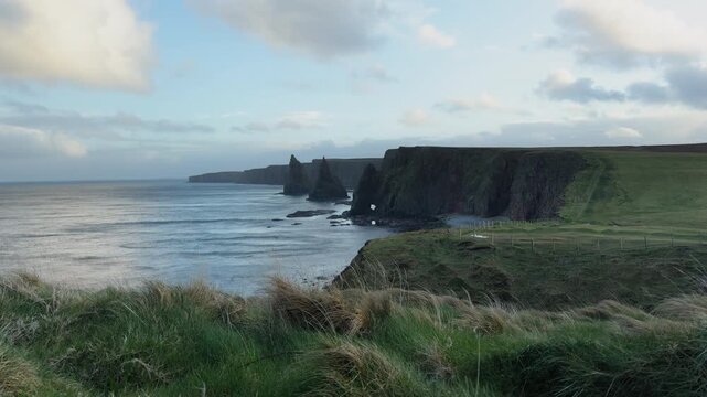 Duncansby Stacks coastal cliffs with ocean waves under soft light in rugged Scottish shoreline landscape