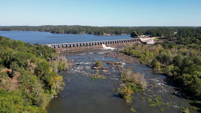Oliver Dam on Chattahoochee River between Columbus Georgia and Phenix City Alabama built 1959 by Georgia Power forms Lake Oliver with spillway crest and exposed downstream channel, drone forward glide