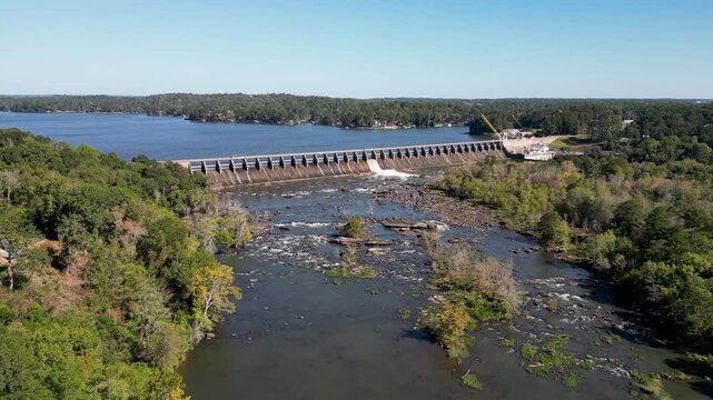 Oliver Dam on Chattahoochee River in Columbus Georgia near Phenix City Alabama regulates flow forming Lake Oliver reservoir with spillway crest and exposed downstream channel as drone slow pullback