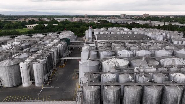 Gallo Winery industrial facility in Modesto California with extensive rows of stainless steel tanks and production buildings. Large scale wine manufacturing operations. Aerial lateral wide shot.