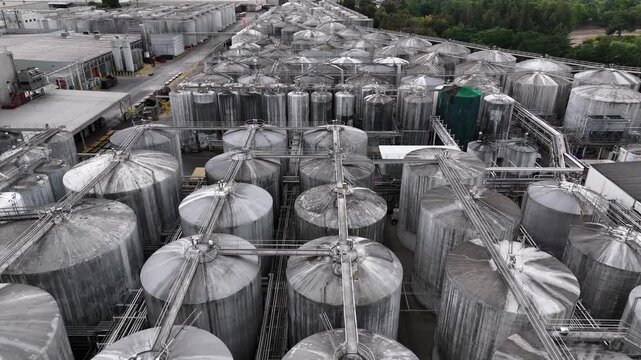Large industrial wine storage facility with rows of stainless steel tanks at Gallo Winery in Modesto California, showing production infrastructure and scale of winemaking operations. Aerial flyover.
