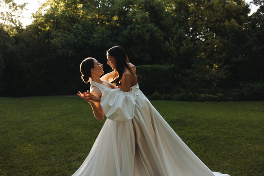 Two brides dancing together in a serene outdoor garden setting