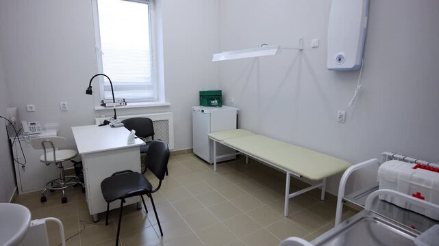 Clean medical examination room offers professional setup with desk seating and bed. Equipment details include spacious storage units