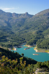 Fototapeta premium Guadalest reservoir turquoise water reflecting mountains and blue sky, beautiful natural landscape of alicante, spain