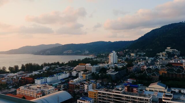Panning aerial shot of coastal city buildings nestled among beach golden hour sunset in Patong, Phuket, Thailand. &middot; 4K DCI 25fps