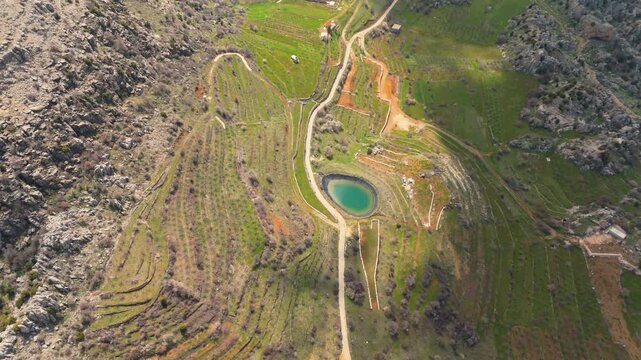 Drone footage over terraced farmland and a small blue pond in Douma, Lebanon, showing the village&rsquo;s agricultural landscape and mountain terrain.
