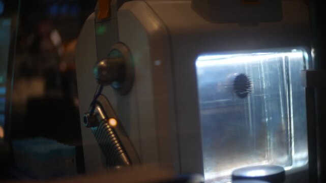 Machine module glowing beside medical tubes in a dark scientific laboratory. Close-up of illuminated biotech equipment operating in a futuristic research workspace