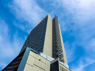 Obraz premium Building stands tall against blue sky with white clouds seen from below during daylight hours