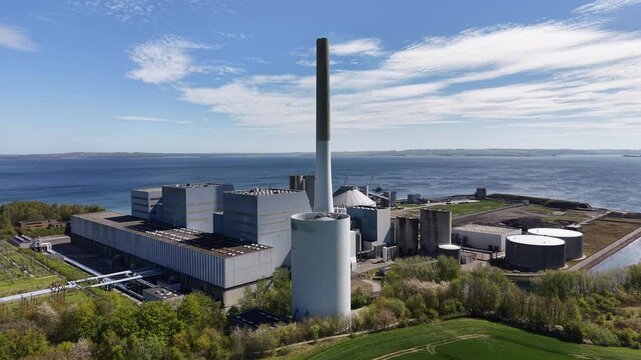 An orbiting drone shot showing the scale of the power station buildings integrated into the coastal Danish landscape.