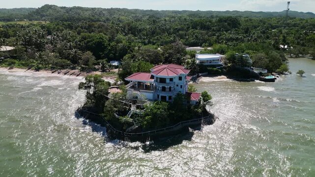 Aerial orbit of Roca Encantada, a historic heritage house on a small coastal island in Guimaras, Philippines with surrounding shoreline and tropical setting.