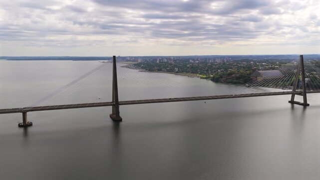 The San Roque Gonz&aacute;lez de Santa Cruz Bridge spans calm waters under a cloudy sky, linking Argentina and Paraguay. Ideal for documentaries on infrastructure or travel content.