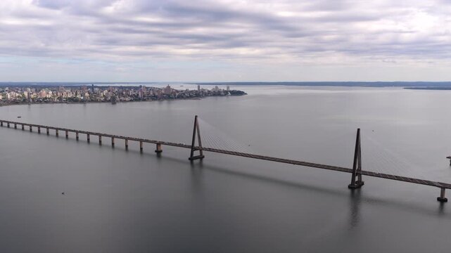 The San Roque Gonz&aacute;lez Bridge extends across the water, connecting Posadas, Argentina, and Encarnaci&oacute;n, Paraguay under a cloud-filled sky. Suitable for travel or documentary projects.