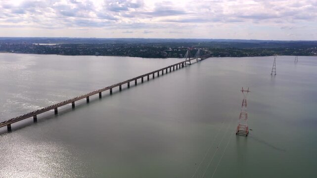 The San Roque Gonz&aacute;lez de Santa Cruz Bridge stretches across a wide expanse of water. Overcast skies create a muted atmosphere. Suitable for infrastructure or travel content.